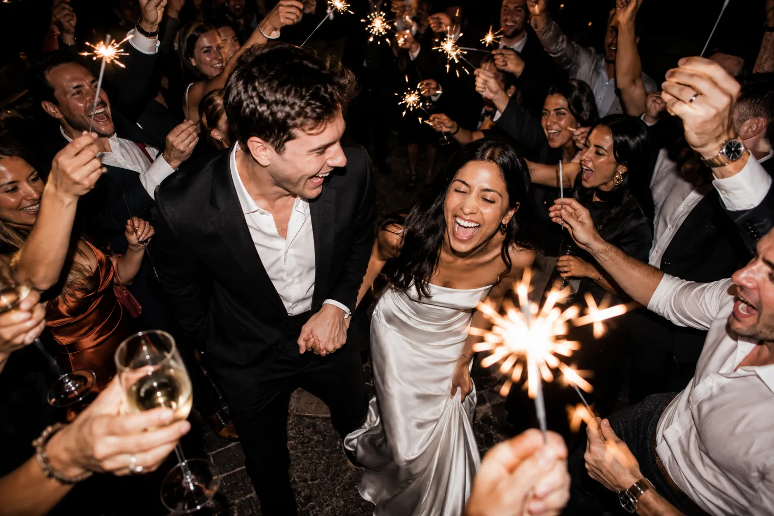 A couple celebrating on their wedding night, champagne raised, mid-dance